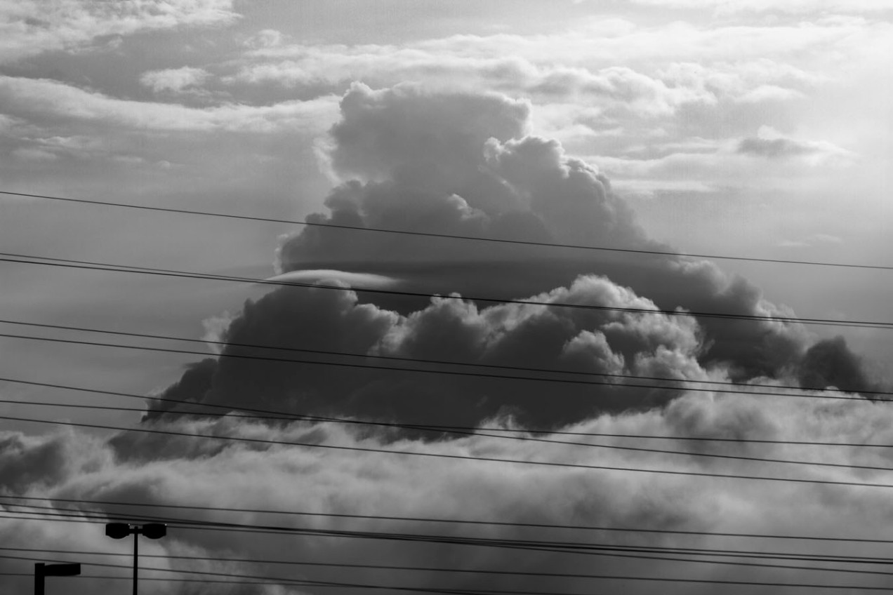 black and white cloud looming behind power lines
